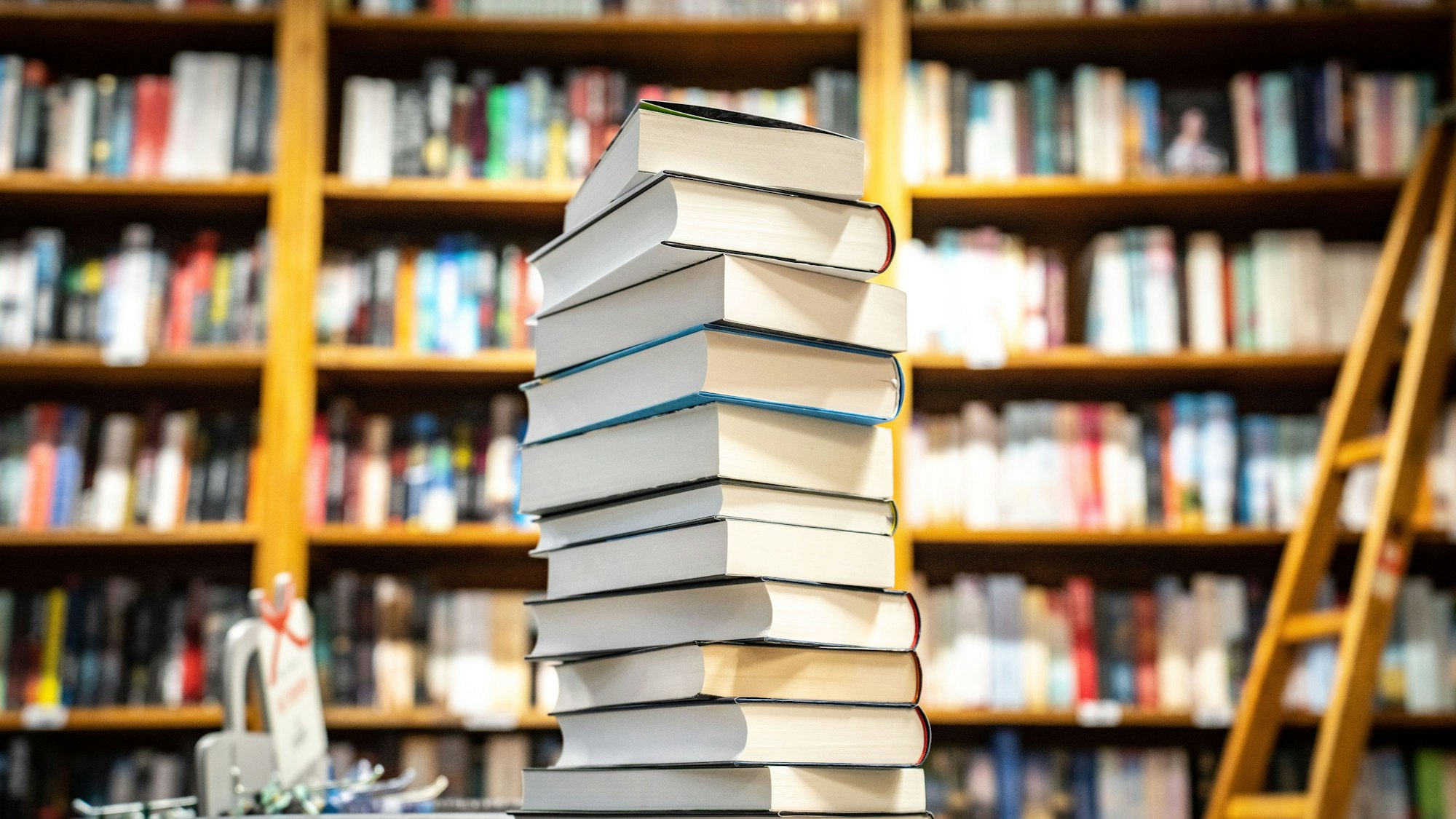 Ein Stapel mit neu erschienenen Büchern liegt in einer Buchhandlung auf einem Verkaufstisch.