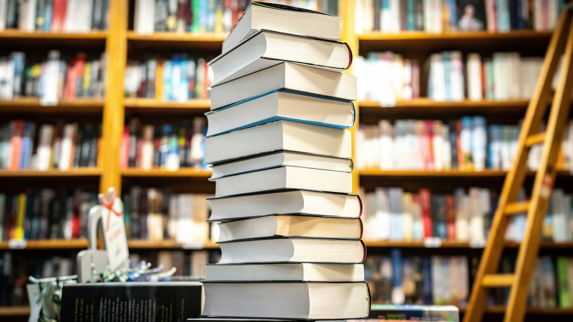 Ein Bücherstapel steht vor einem Bücherregal.