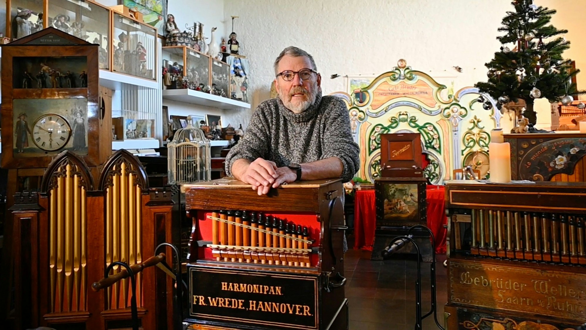 Ein Mann lehnt an einer Drehorgel.
