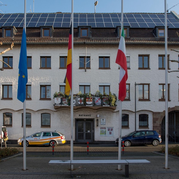 Autos parken in der Abendsonne vor dem Zülpicher Rathaus.