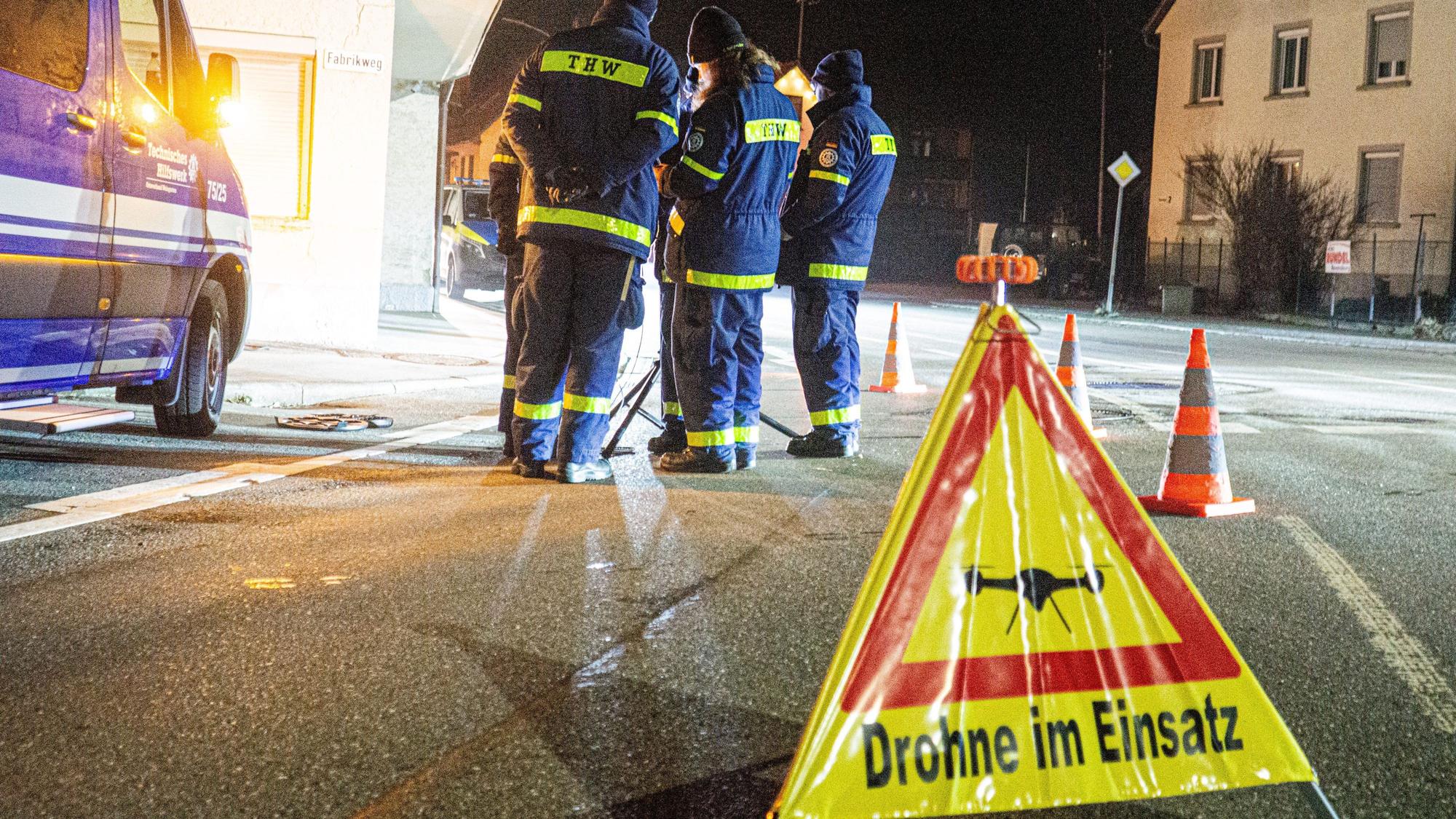 Mitglieder des THW im Einsatz. Im Vordergrund ein Warnschild „Drohne im Einsatz“.