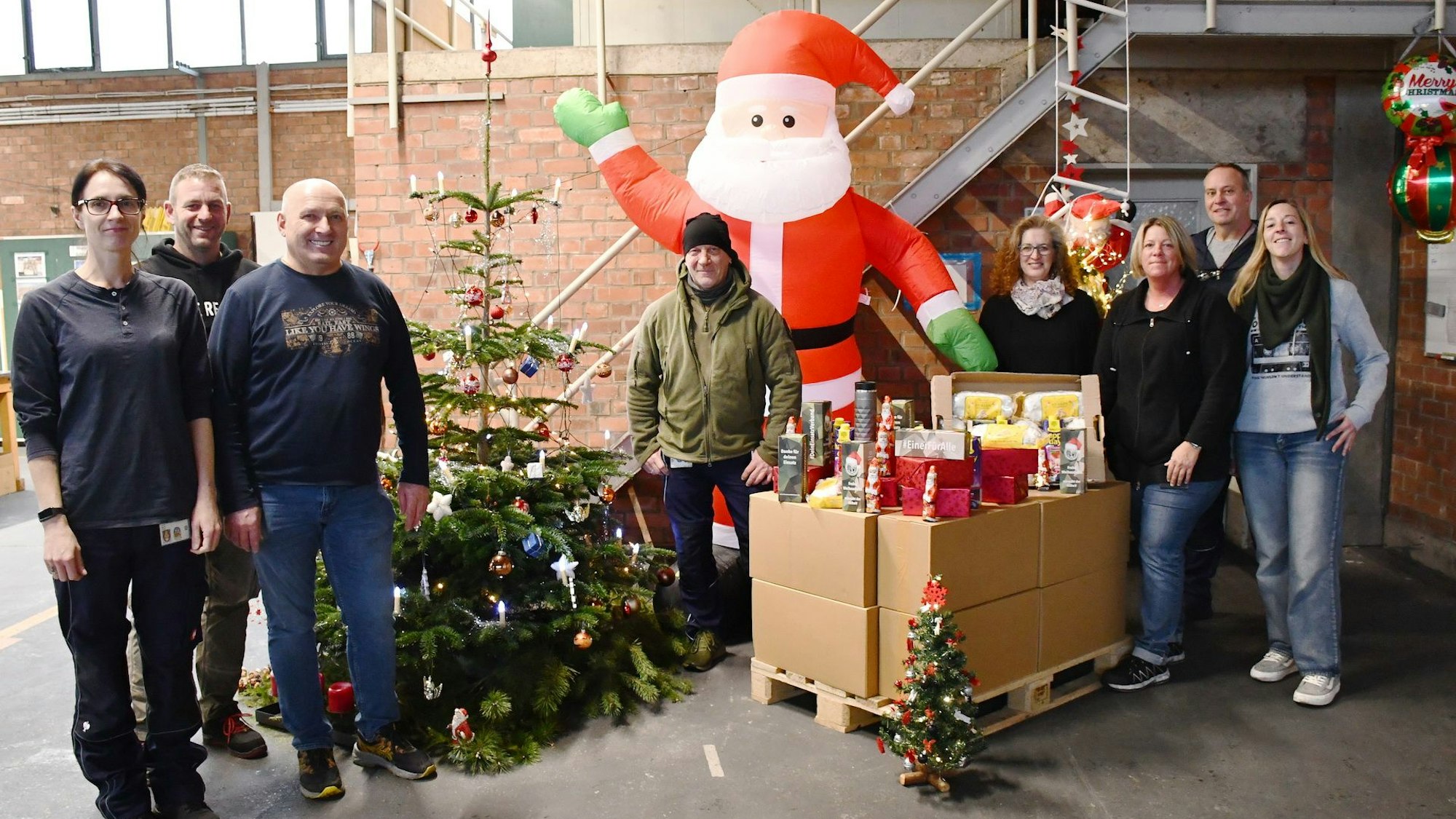 Die Mitarbeiter des Transitzentrums der Bundeswehr in Mechernich mit Weihnachtsmann-Figur, Weihnachtsbaum und einer Palette voller Präsente.