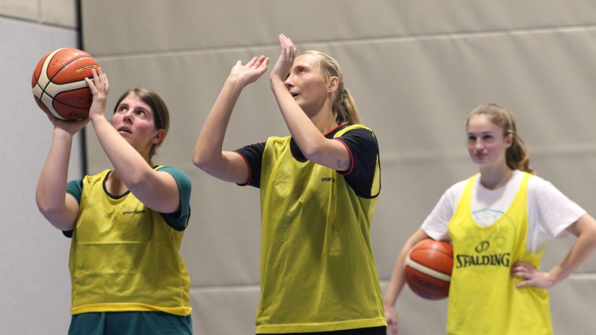 Julia Reuß hält einen Basketball in den Händen, neben ihr steht eine Basketballerin der ErftBaskets und erklärt ihr die richtige Wurftechnik.