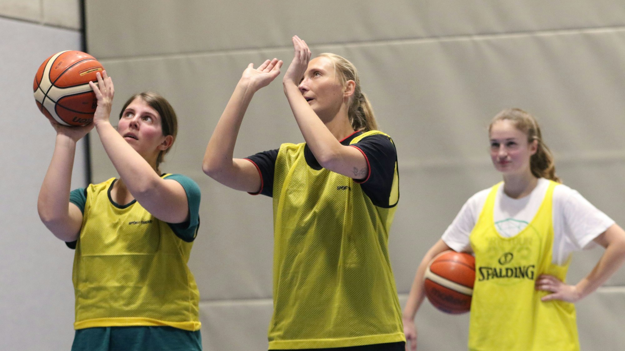 Julia Reuß hält einen Basketball in den Händen, neben ihr steht eine Basketballerin der ErftBaskets und erklärt ihr die richtige Wurftechnik.