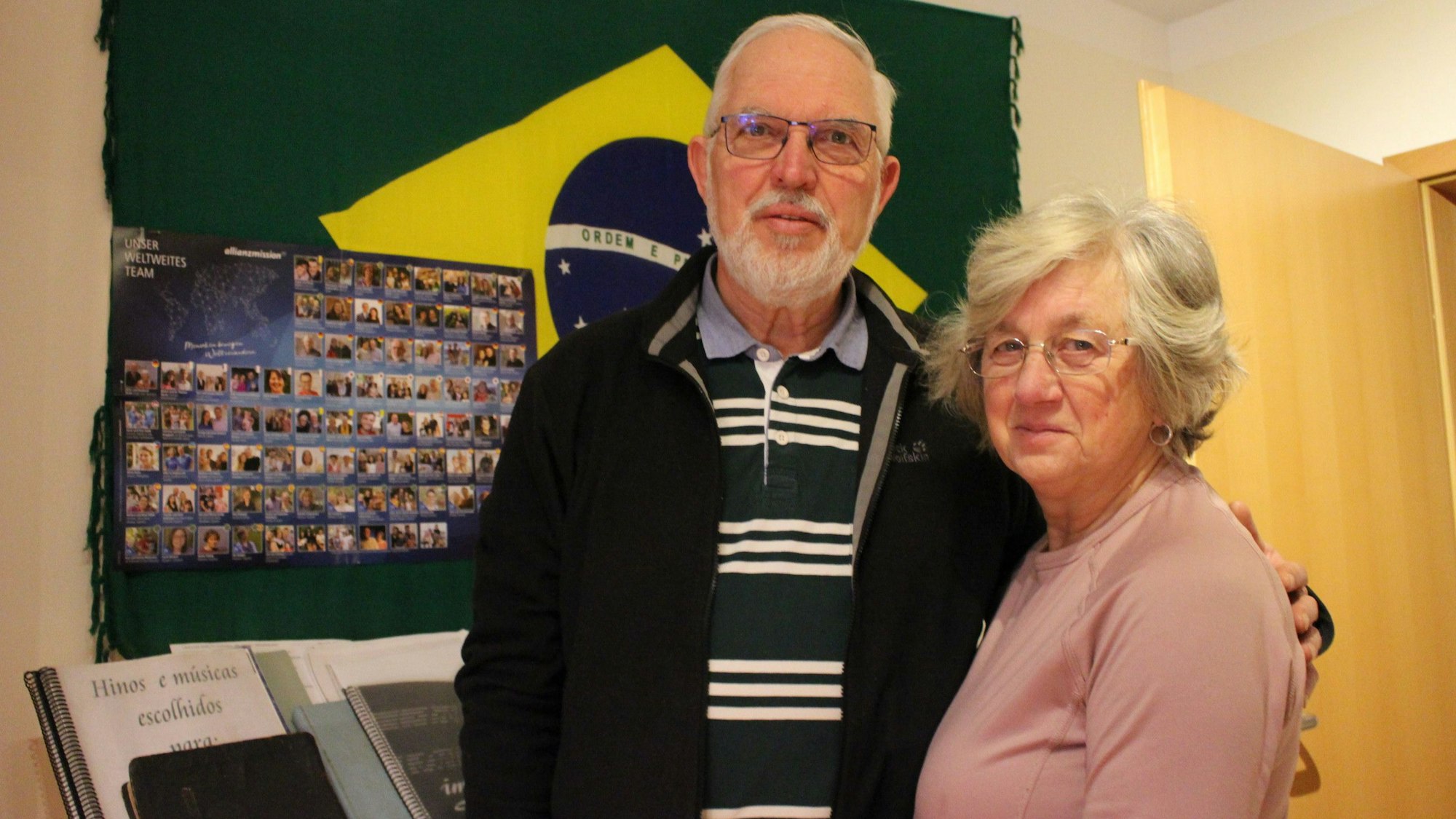 Krista und Walter Feckinghaus stehen vor einer Brasilien-Flagge in seinem Arbeitszimmer in Oberwichterich.