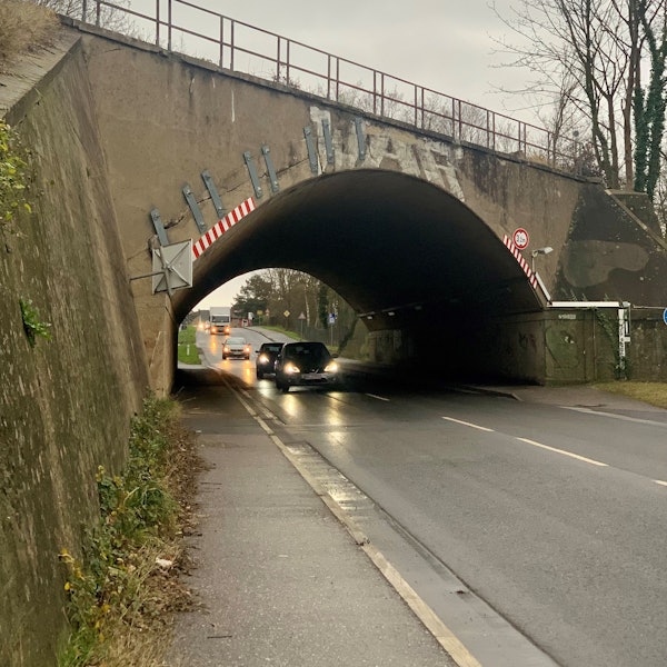 Unter einer Brücke fahren Autos hindurch.