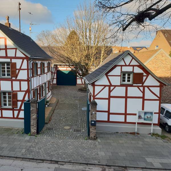 Ein Ensemble aus Fachwerkgebäuden umgibt einen Hof mit einer großen Linde.