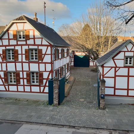 Ein Ensemble aus Fachwerkgebäuden umgibt einen Hof mit einer großen Linde.