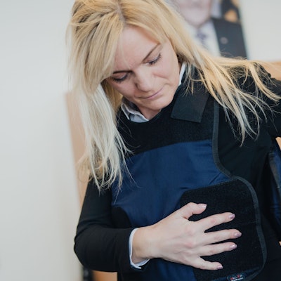 Gerichtsvollzieherin Georgia Papapostolou zieht während eines Pressetermins ihre neue Schutzweste an. Im Amtsgericht Köln wurden die ersten von landesweit 750 Schutzwesten für Gerichtsvollzieher übergeben.