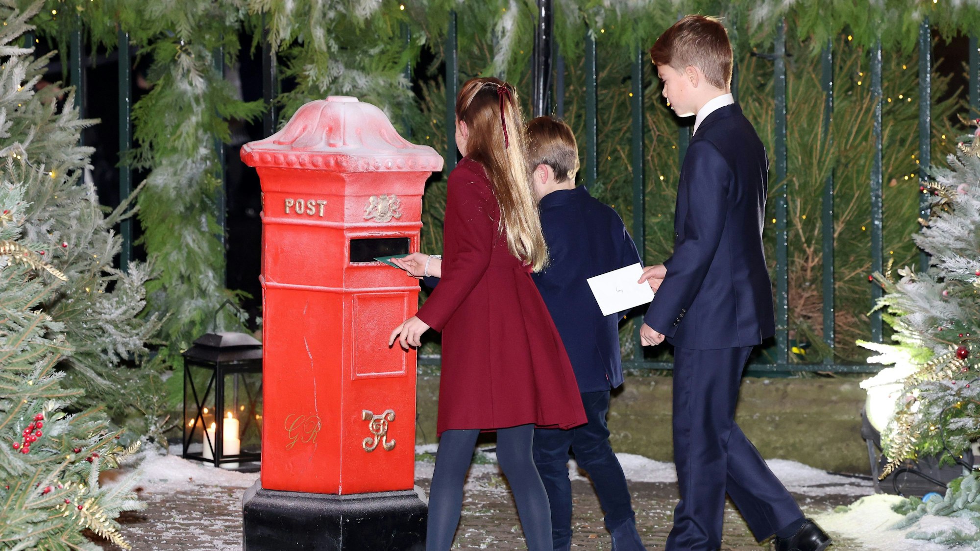 08.12.2023, Großbritannien, London: Prinzessin Charlotte (l-r), Prinz Louis und Prinz George von Wales werfen vor dem Gottesdienst «Royal Carols - Together At Christmas» in der Westminster Abbey Briefe in einen Postkasten ein.