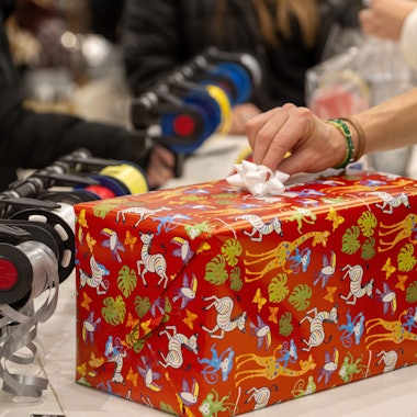 In einem Kaufhaus verpackt eine Verkäuferin für Kunden ein Weihnachtsgeschenk.