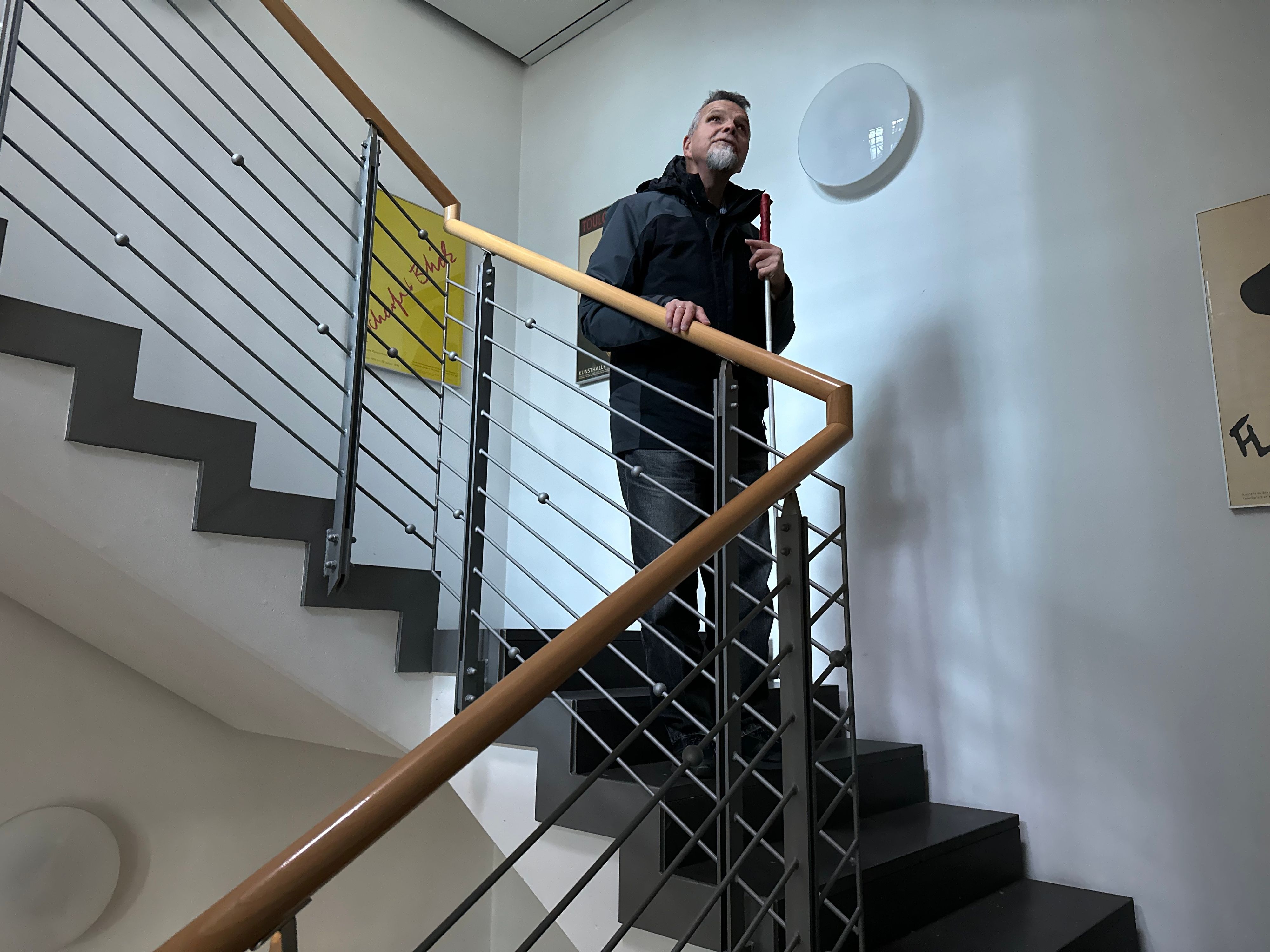 Günther Heger greift an ein Treppengeländer, so fühlt er wie es auf und ab geht.