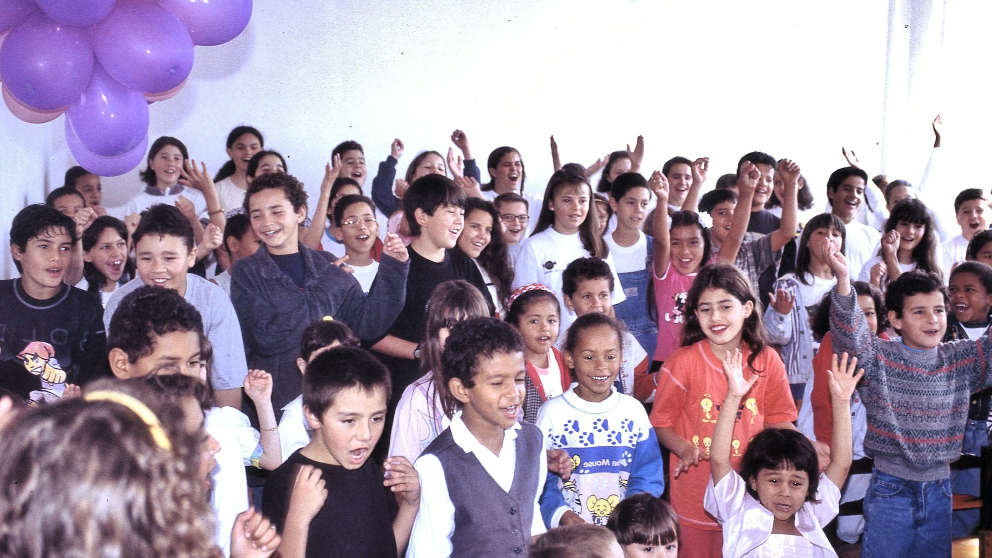 Das Foto zeigt etwa 50 Kinder, die fröhlich singen und tanzen.