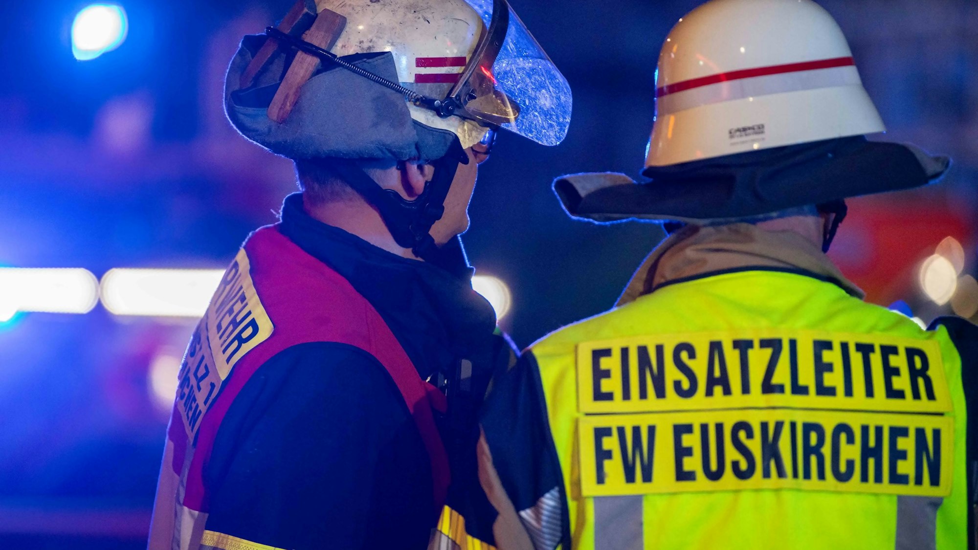 Das Symbolbild zeigt einen Einsatzleiter der Euskirchener Feuerwehr, der sich an einem Einsatzort mit einem Kollegen bespricht.