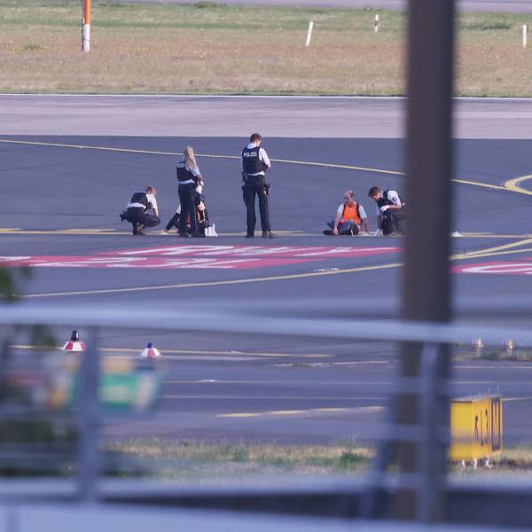 Polizistinnen und Polizisten stehen neben Mitgliedern der Klima-Gruppe Letzte Generation, die sich im Juli 2023 auf dem Rollfeld am Düsseldorfer Flughafen festgeklebt haben.