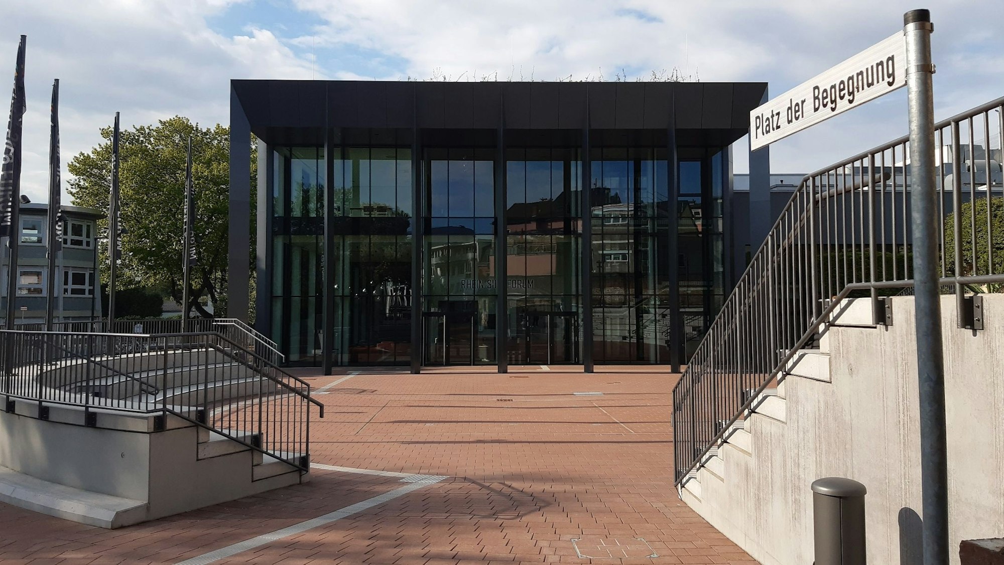 Ein Platz mit zwei kleinen Tribünen und das verglaste Foyer einer Veranstaltungshalle im Hintergrund.