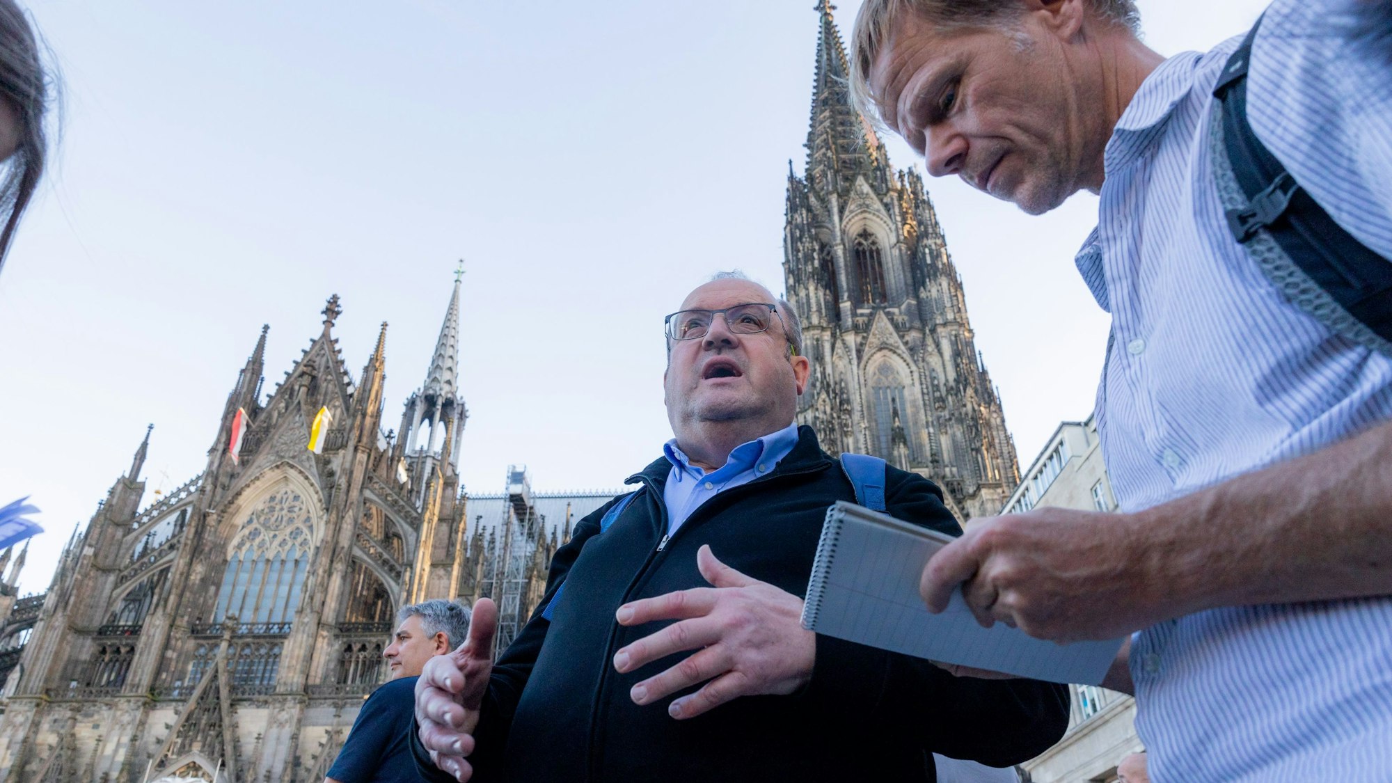 Monsignore Herbert Ullmann steht vor dem Kölner Dom und unterhält sich.