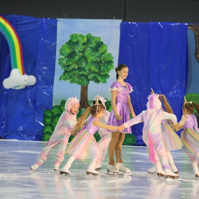 Als Einhörner verkleidete Mädchen mit Schlittschuhen auf dem Eis.