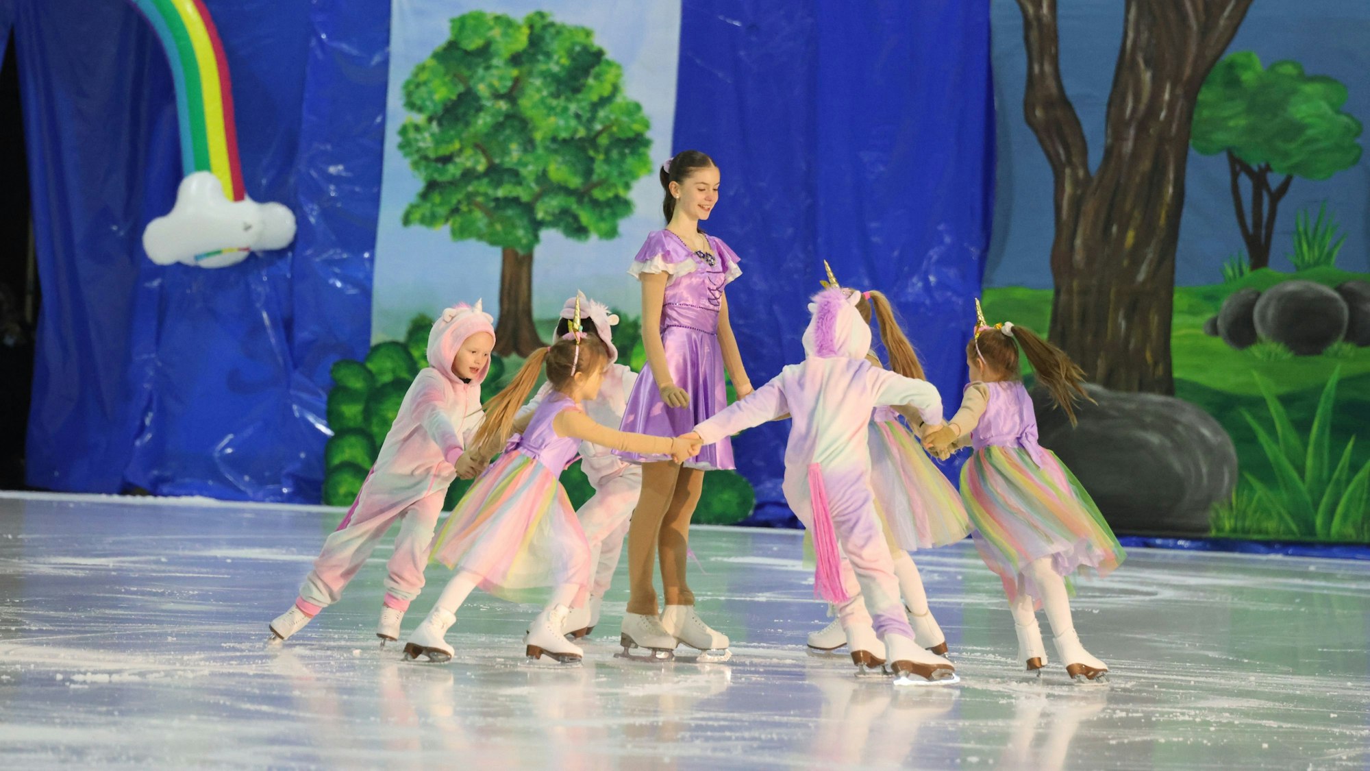 Als Einhörner verkleidete Mädchen mit Schlittschuhen auf dem Eis.