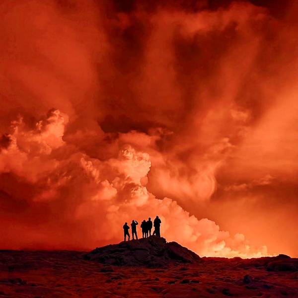Vulkanausbruch auf Island: Drei Personen beobachten Magma, Lava und den orangem Himmel.