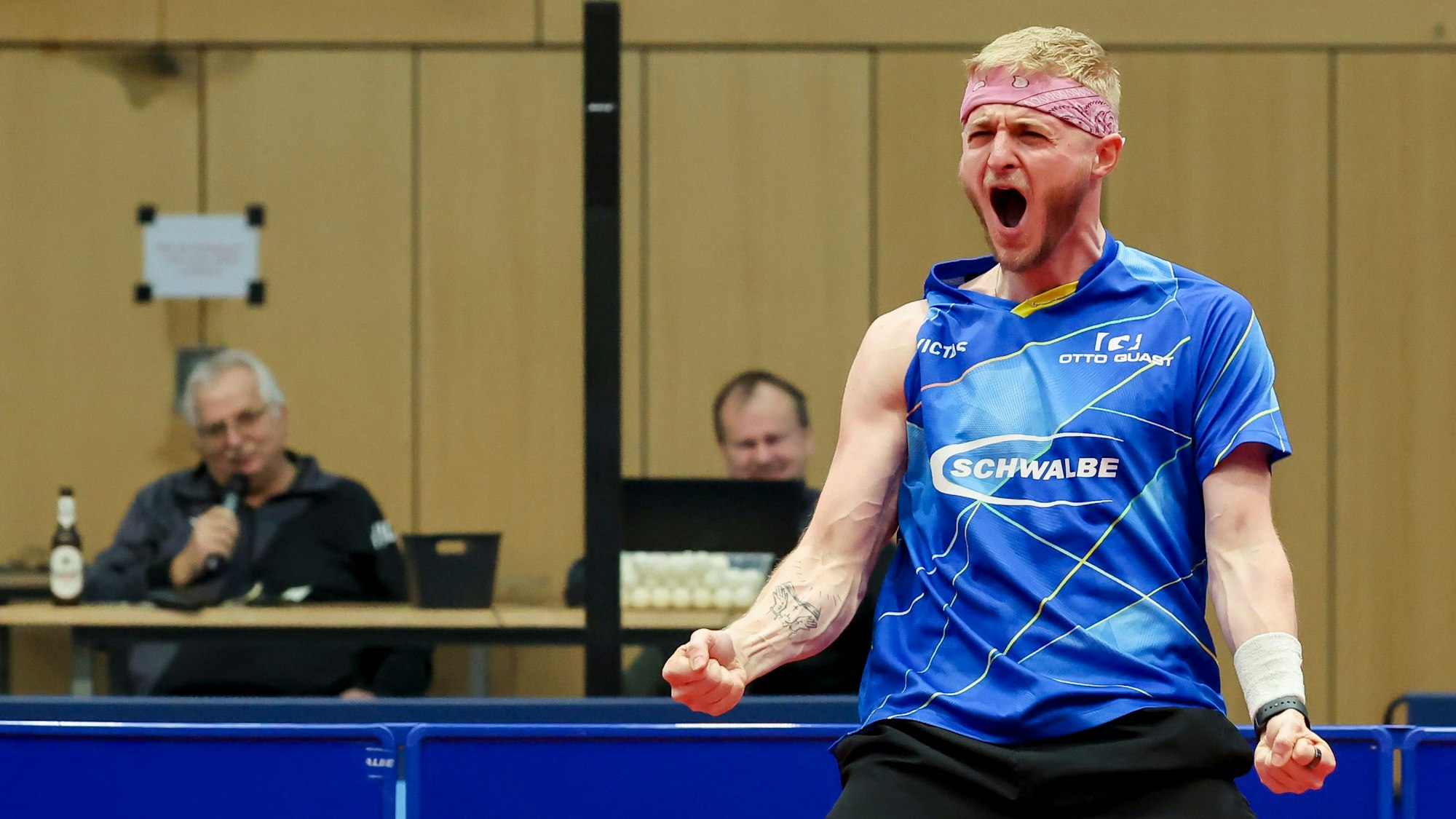 Tischtennis-Profi Romain Ruiz steht an einer Tischtennisplatte und jubelt lautstark.