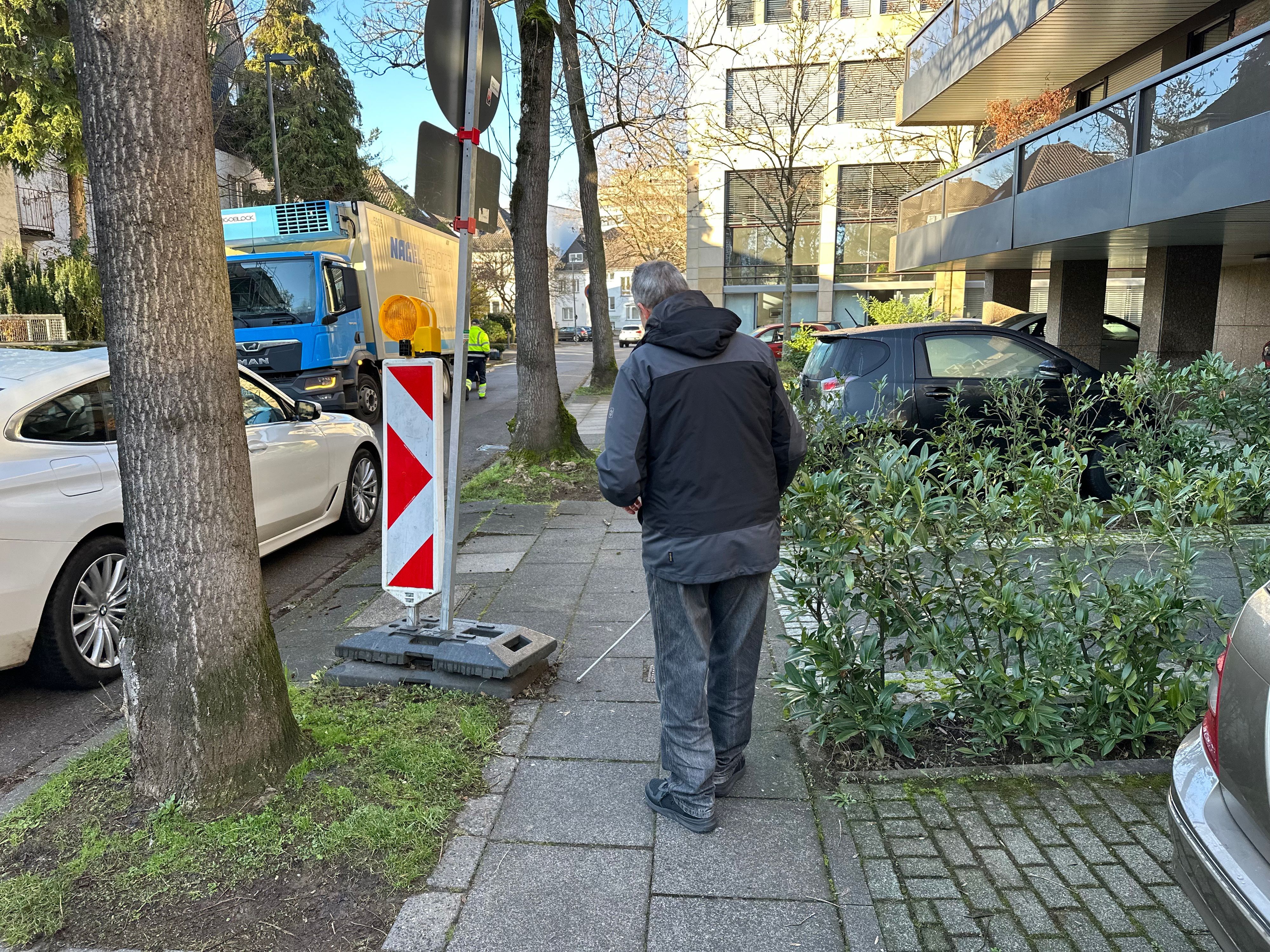 Günther Heger tastet mit seinem Blindenstock den Weg. Er hört ein Auto, das nah an ihn heranfährt, ein plötzlich aufgebautes Baustellenschuld erkennt er sicher.