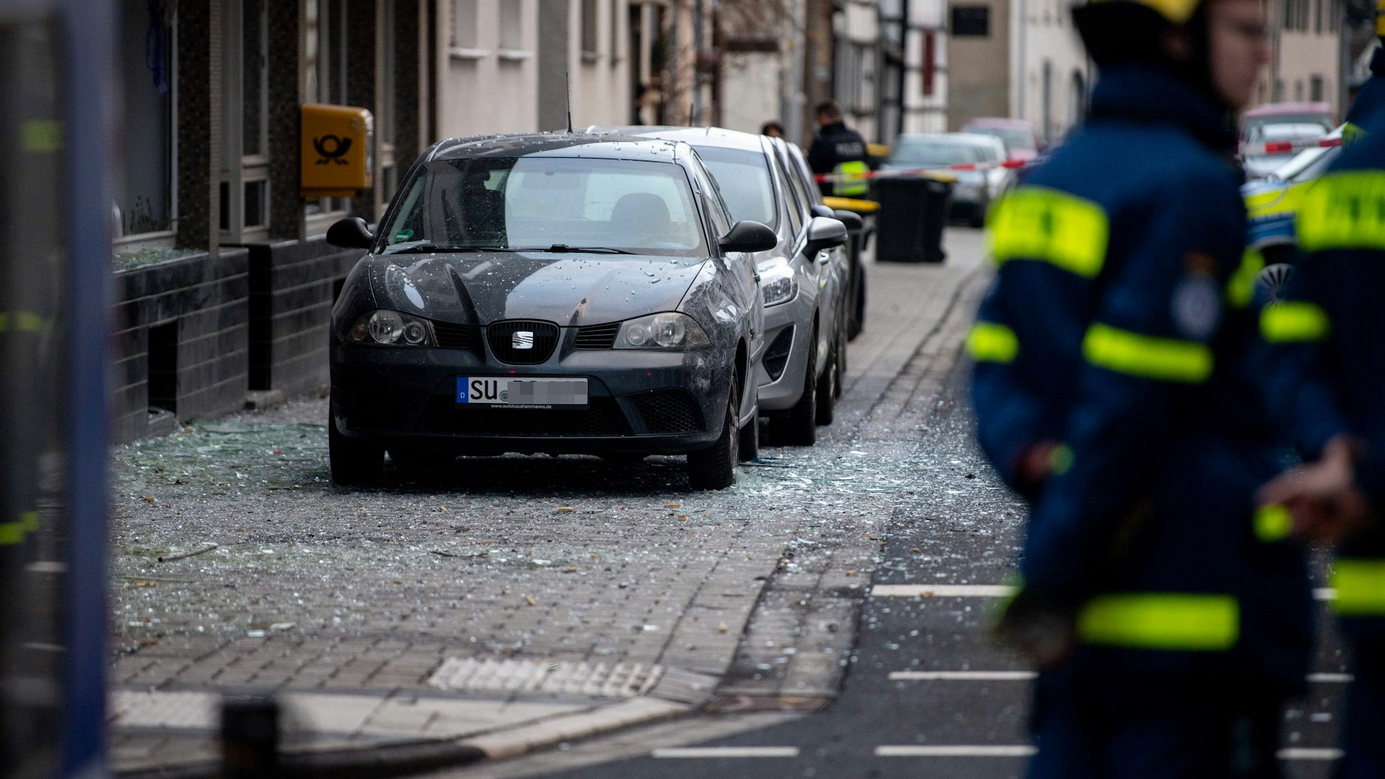 Das Bild zeigt ein Auto, das in einem wahren Scherbenmeer steht. Im Vordergrund stehen zwei Mitarbeiter des THW.