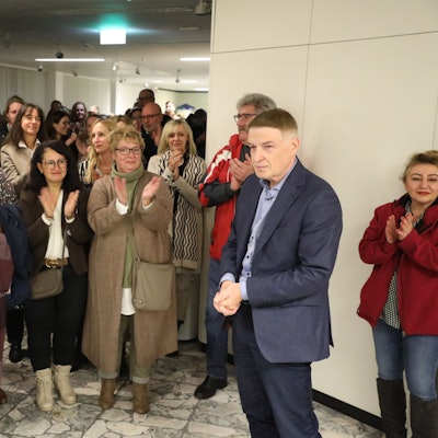 Kreisdirektor Dr. Erik Werdel steht vor der Tür des großen Sitzungssaals im Kreishaus am Rübezahlwald in Bergisch Gladbach. Mehrere Menschen applaudieren ihm