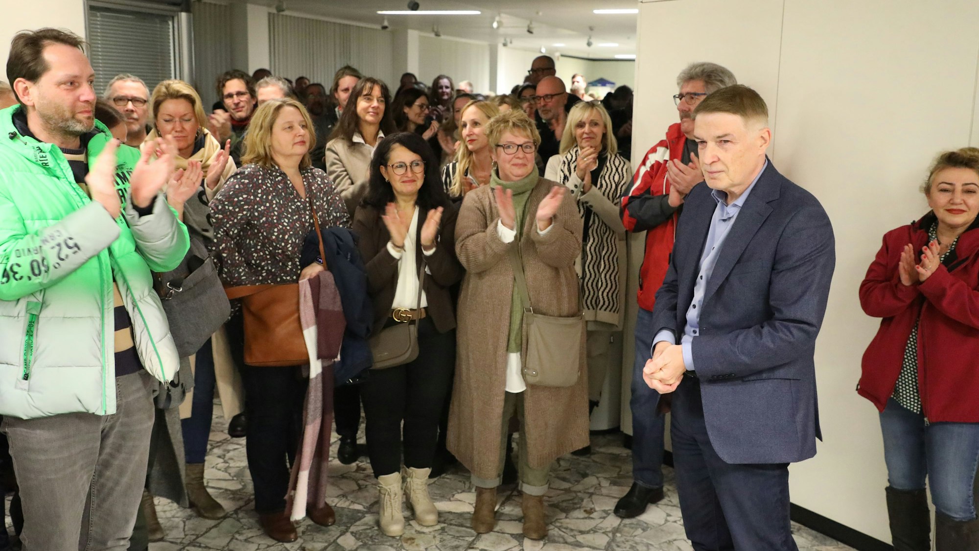 Kreisdirektor Dr. Erik Werdel steht im Foyer des Kreishauses nach der entscheidenden Abstimmung über sein Amt vor Menschen, die ihm applaudieren.