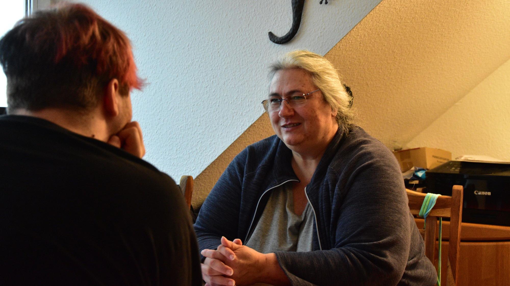 Sohn und Mutter sitzen sich am Tisch gegenüber.