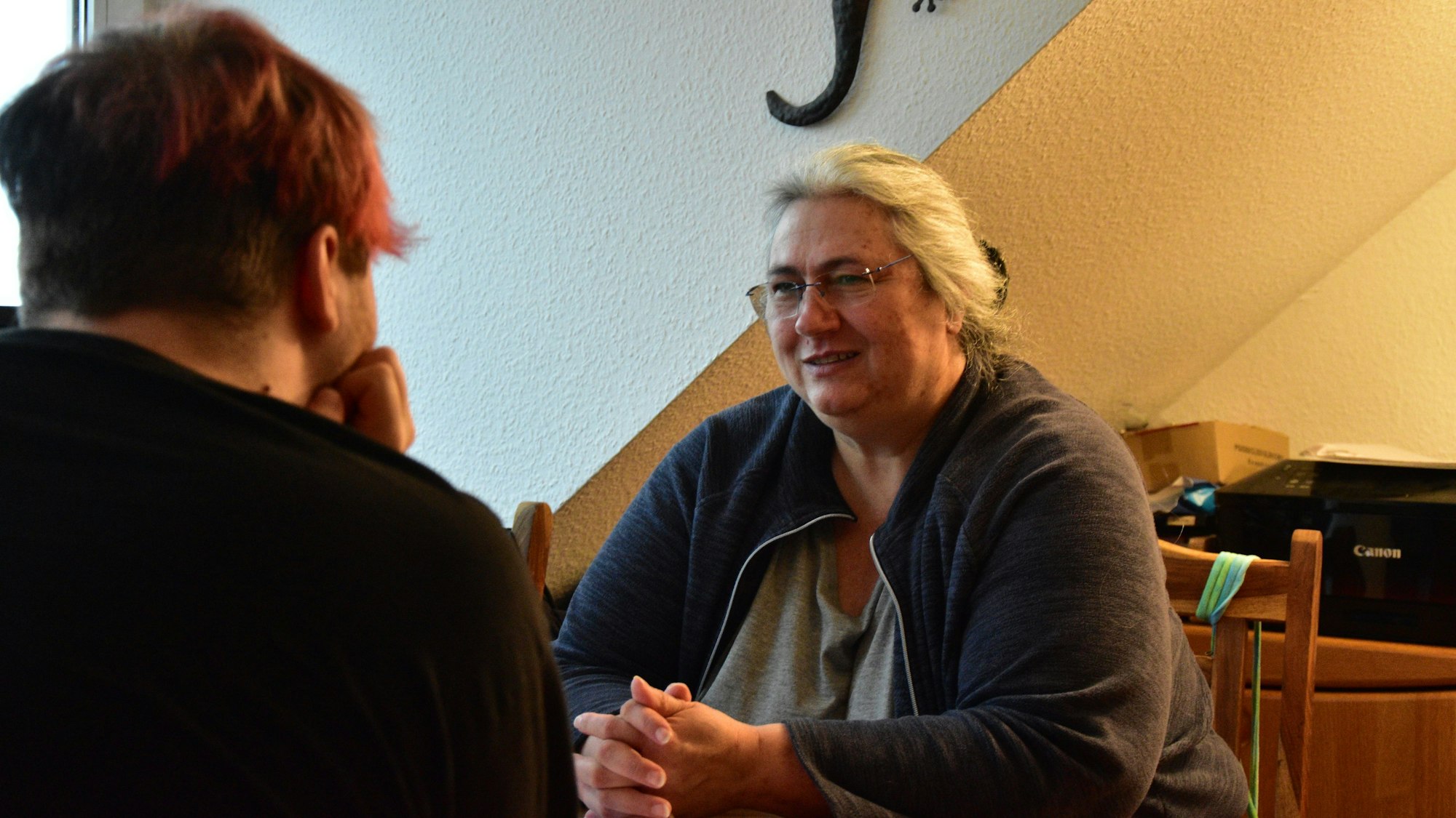 Sohn und Mutter sitzen sich am Tisch gegenüber.