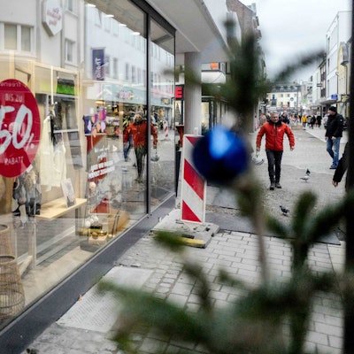 Das Bild zeigt ein Schaufenster in der Euskirchener Innenstadt. Rabatthinweise kleben an der Scheibe, im Vordergrund steht ein Tannenbaum.