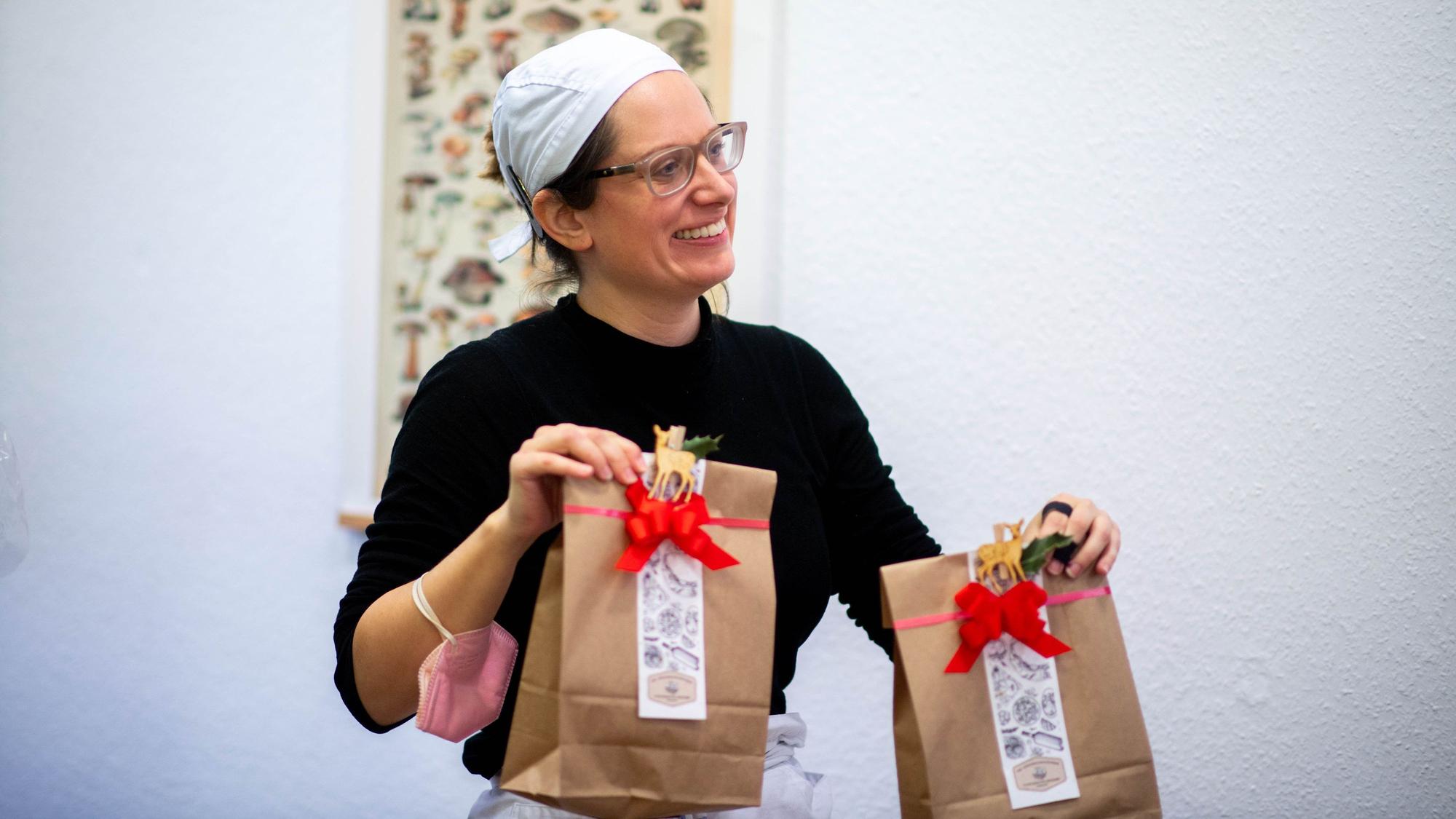 Anika-Helena Wübben trägt zwei Geschenktüten für eine Kundin durch den Laden.