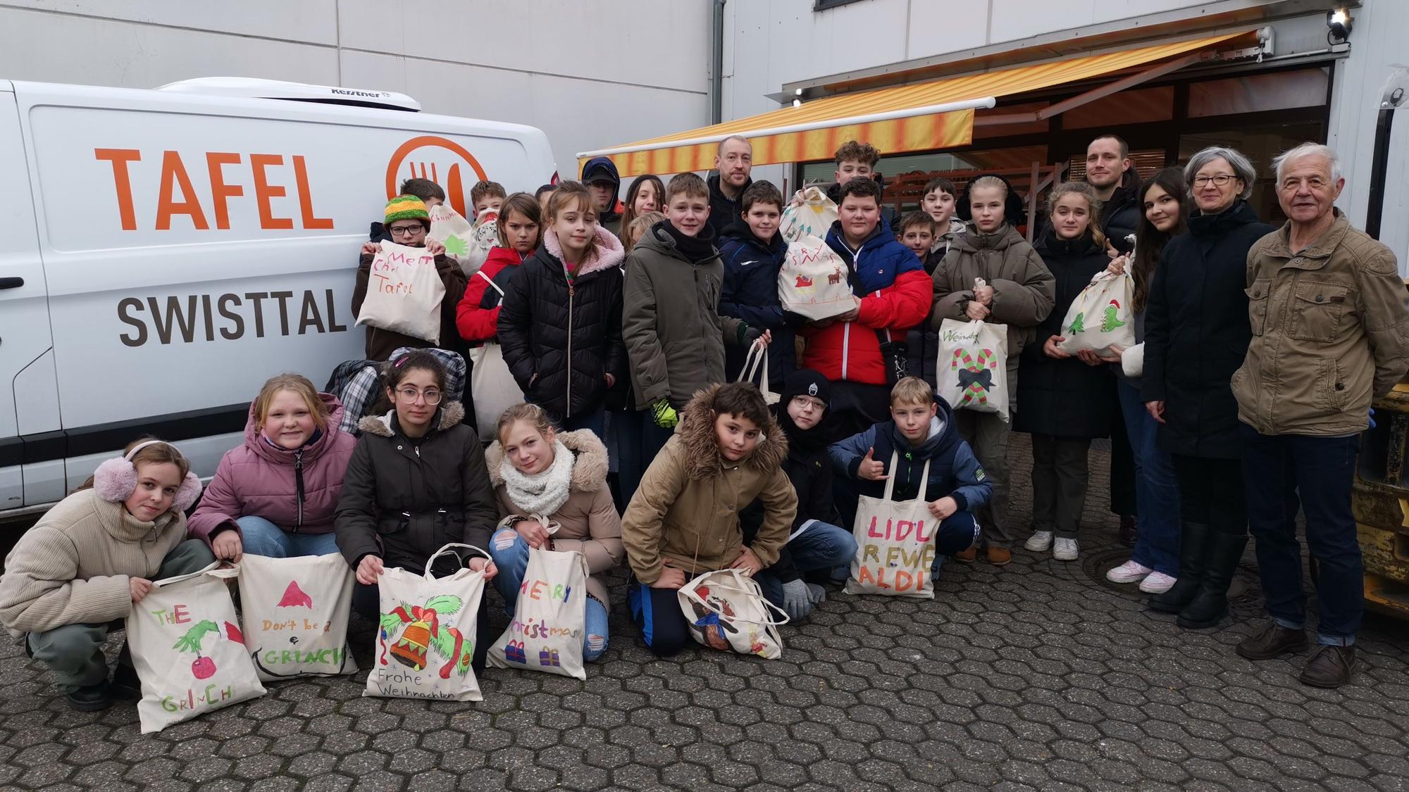 Eine rundum gelungene Aktion: Jürgen Hein (r.) und Sybille Prochnow Penedo mit der 6 b beim Besuch der Tafel im Heimerzheimer Gewerbegebiet. In der Schule waren die Taschen für die Lebensmittel schön gestaltet worden.