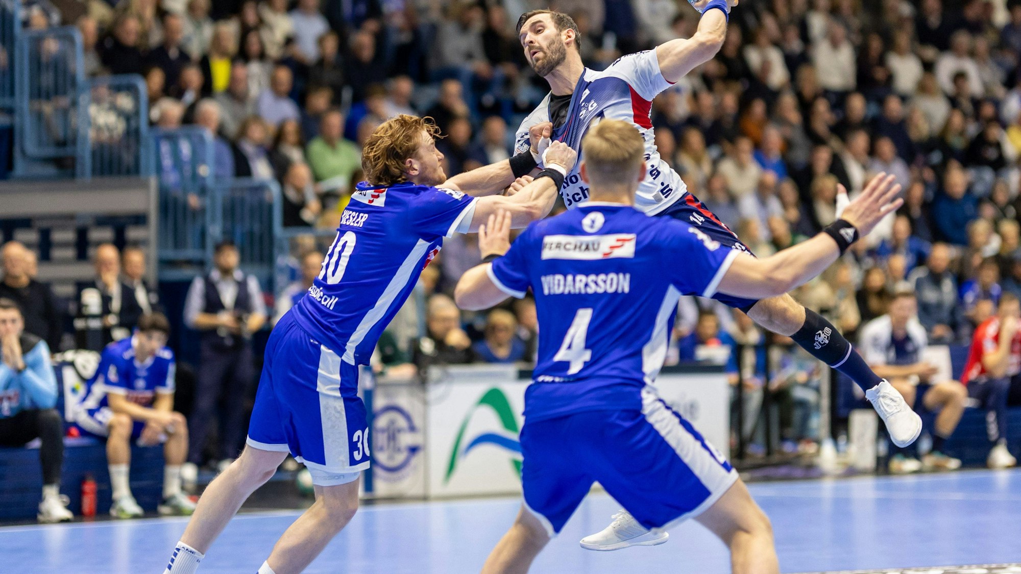 Zwei Gummersbacher Abwehrspieler wehren den hochsteigenden Flensburger Angreifer ab.