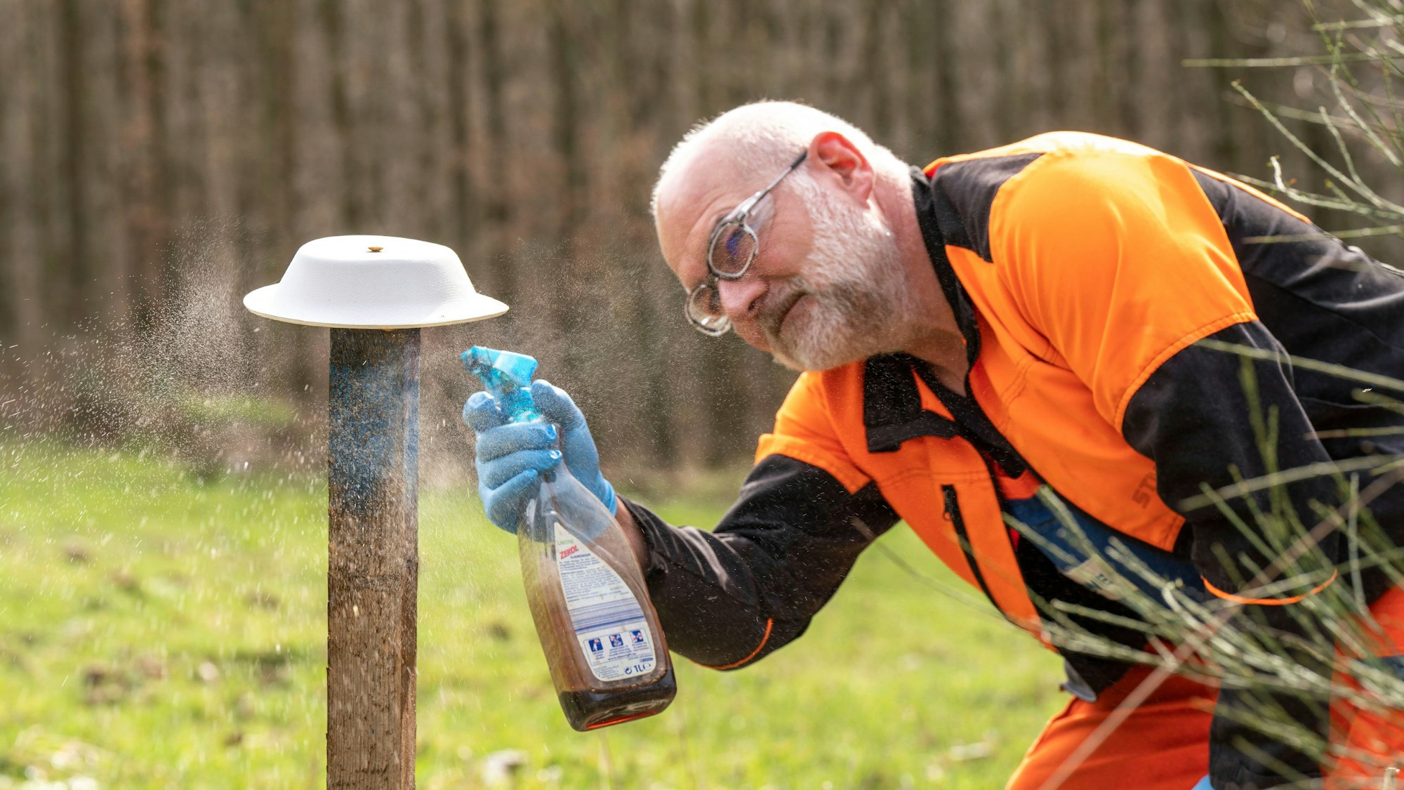 Ein Mann hält eine Sprühflasche in der Hand.