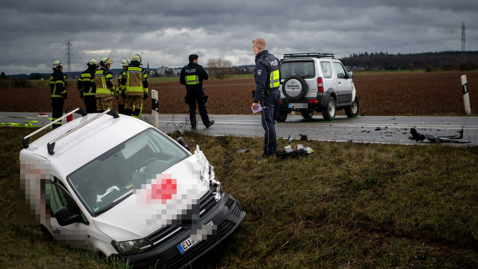 Das Bild zeigt die Szenerie des Unfalls. Ein Auto liegt im Graben, das andere etwa zehn Meter entfernt. Es steht auf der Straße. Auch Polizisten und Feuerwehrleute sind an der Einsatzstelle.