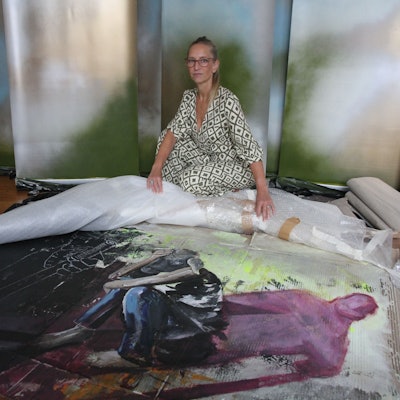 Eine Malerin breitet ein Bild auf dem Boden aus