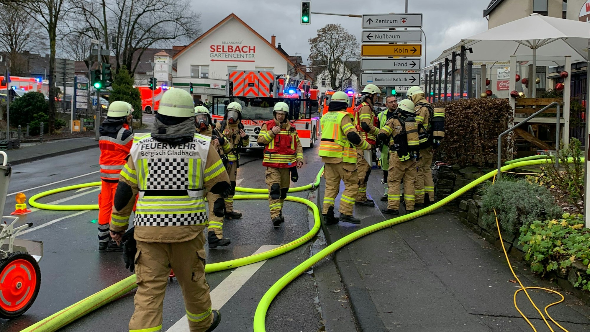 Feuerwehrleute stehen vor einem Wohn- und Geschäftshaus in Bergisch Gladbach-Paffrath.