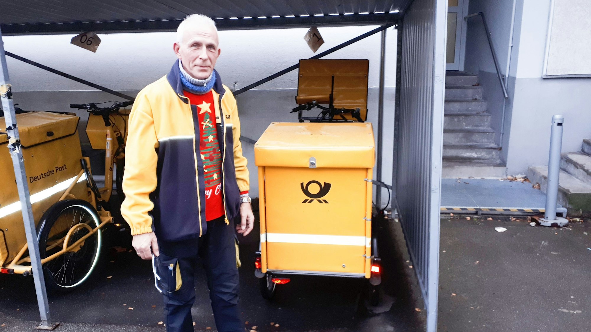 Postbote steht am Fahrrad.