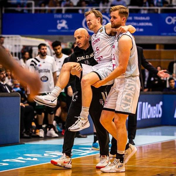 Harald Frey wird von Till Pape und Baskets-Physiotherapeut Bogdan Suciu vom Feld getragen.