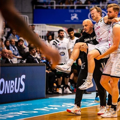 Harald Frey wird von Till Pape und Baskets-Physiotherapeut Bogdan Suciu vom Feld getragen.