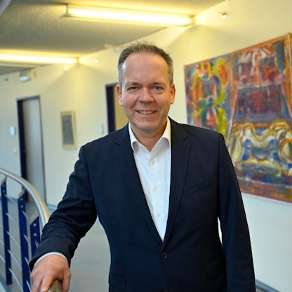 Klaus Grootens vor einem bunten Gemälde im Gummersbacher Kreishaus.