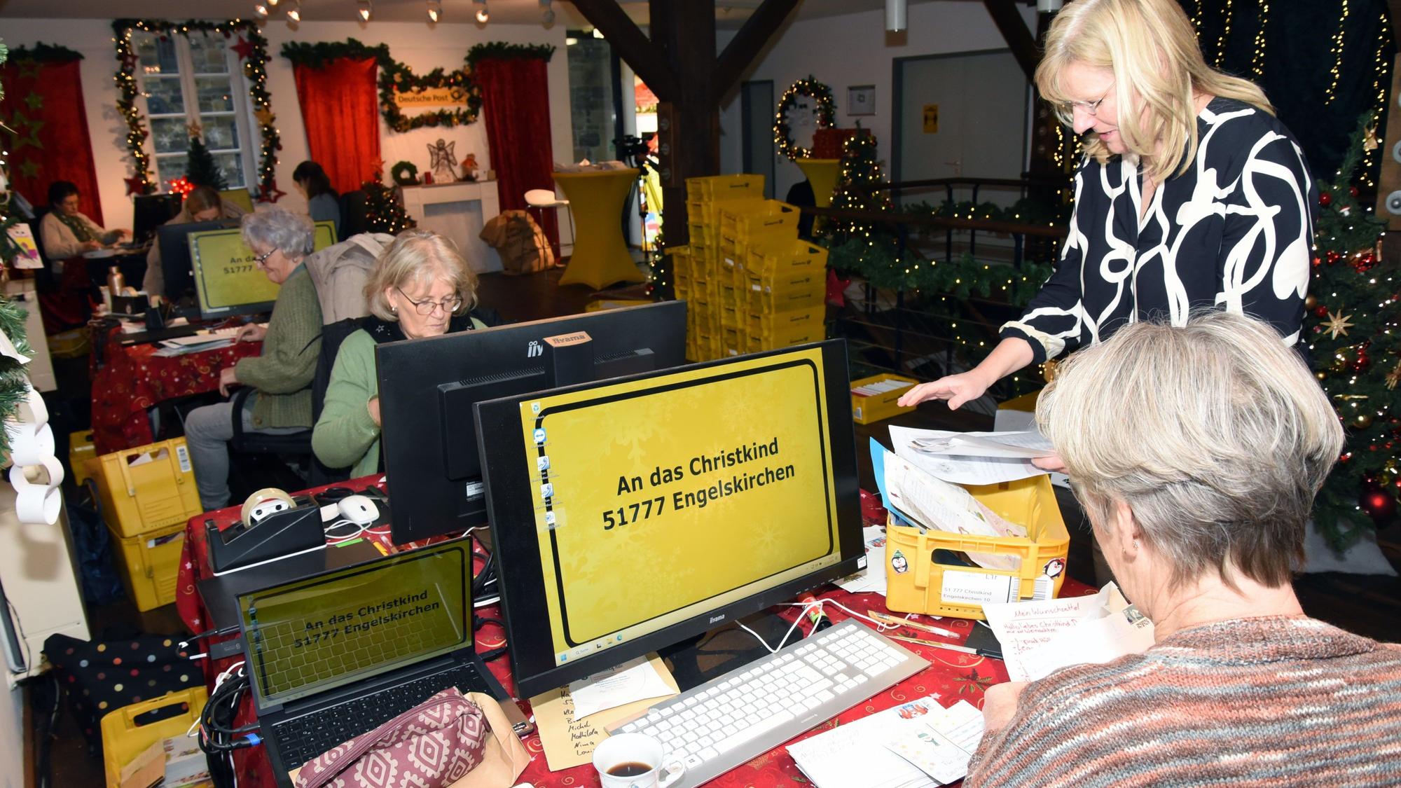 An Tischen im Weihnachtspostamt sitzen Christkindhelferinnen, die Briefumschläge öffnen und Wünsche lesen.