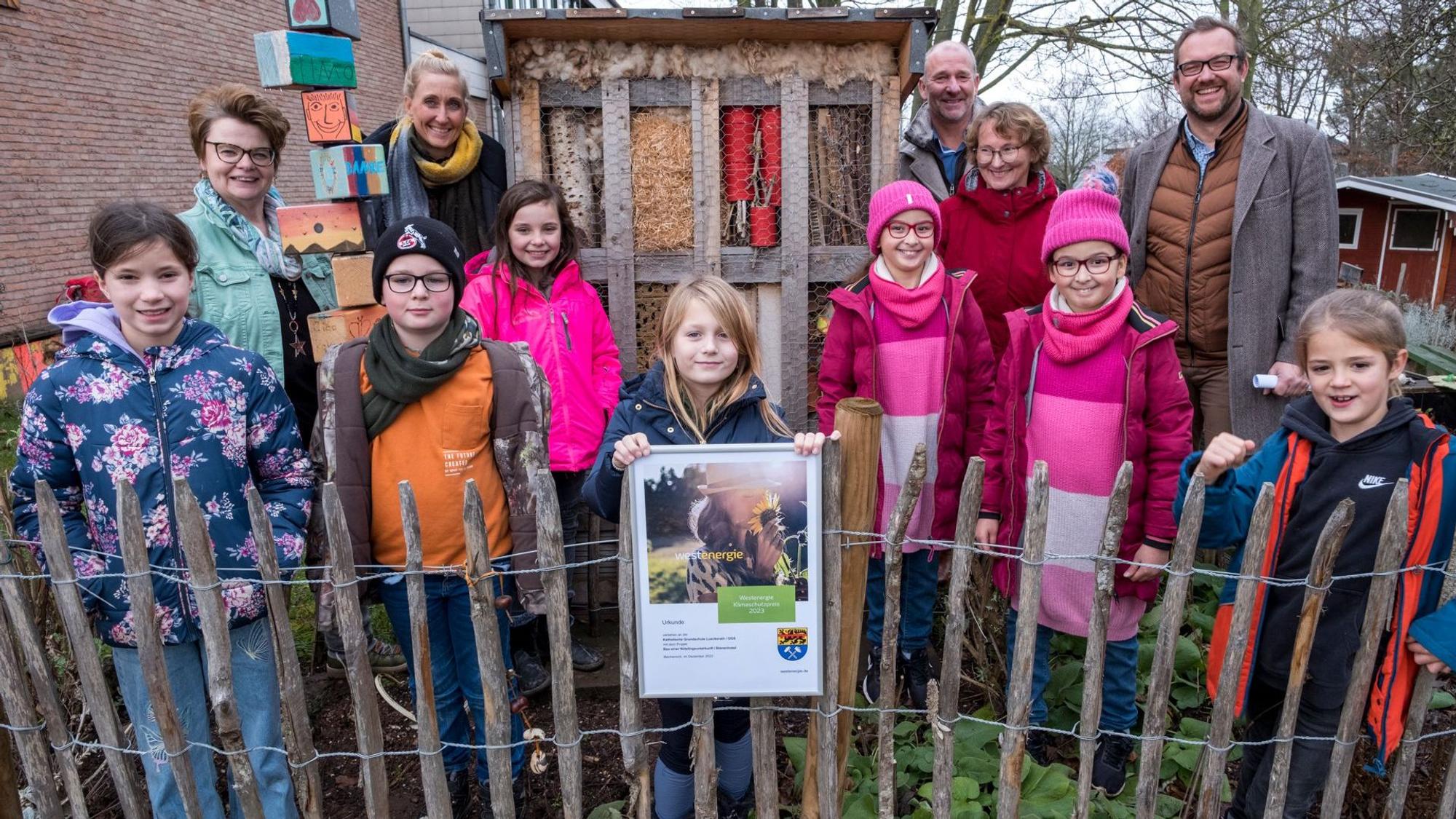 Kinder und Erwachsene stehen vor dem Insektenhotel der Grundschule in Lückerath.