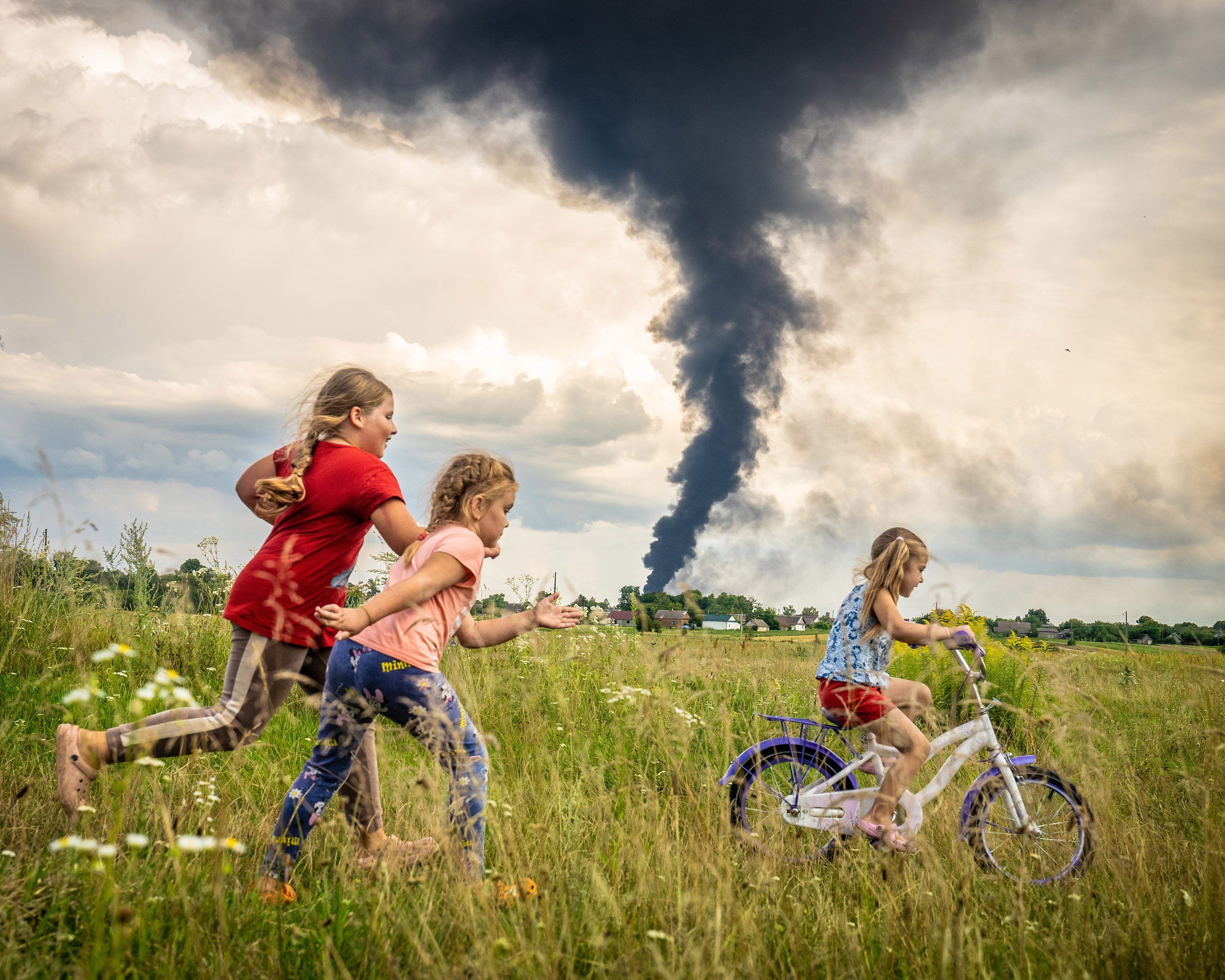 Unter den dunklen Wolken des Krieges übt die fünfjährige Alina, begleitet von Freundinnen, das Fahrradfahren auf einer Wiese im Nordwesten der Ukraine - ein Moment der Unbeschwertheit