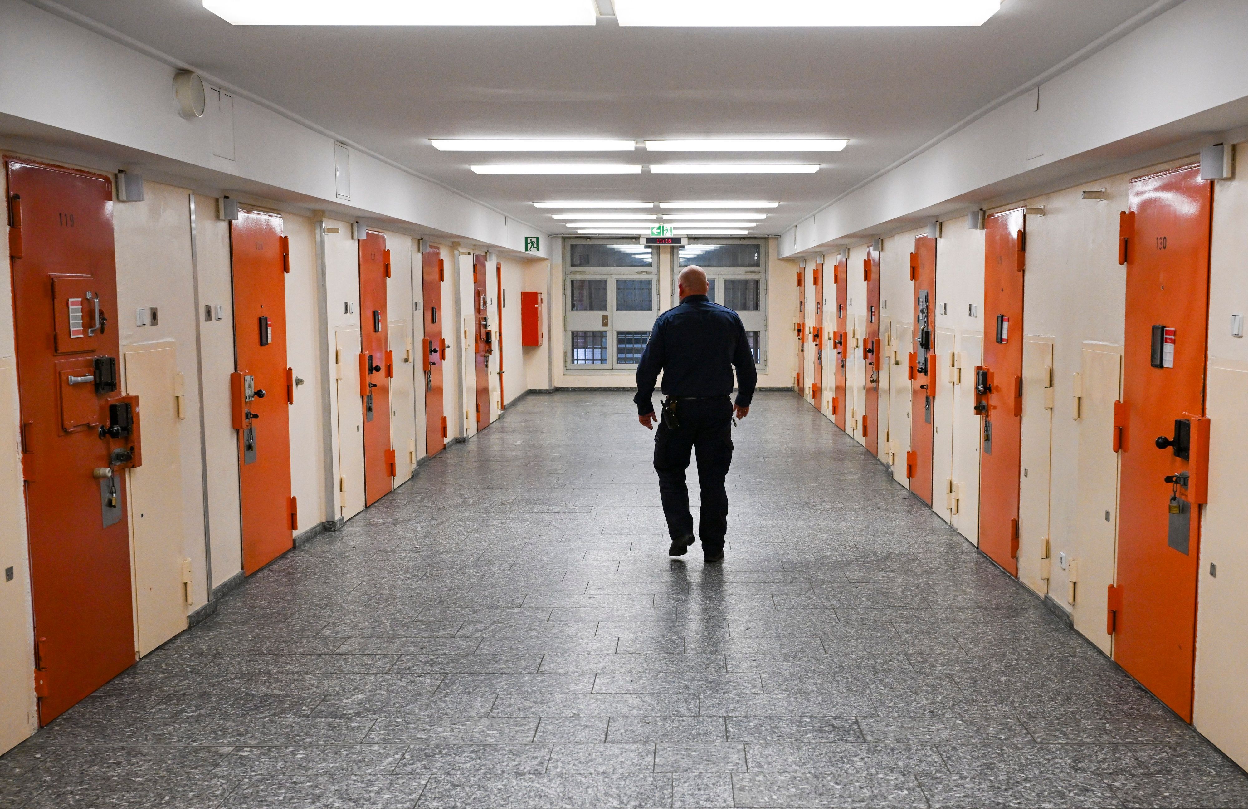 Ein Vollzugsbeamter geht in der Zugangsabteilung der Justizvollzugsanstalt Moabit an Zellentüren vorbei.
