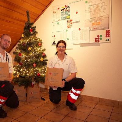 Matthias Unger und Vanessa Siebertz knien in der Rettungswache Tondorf an einem kleinen Weihnachtsbaum, mit dem sie ihre Unterkunft weihnachtlich geschmückt haben.