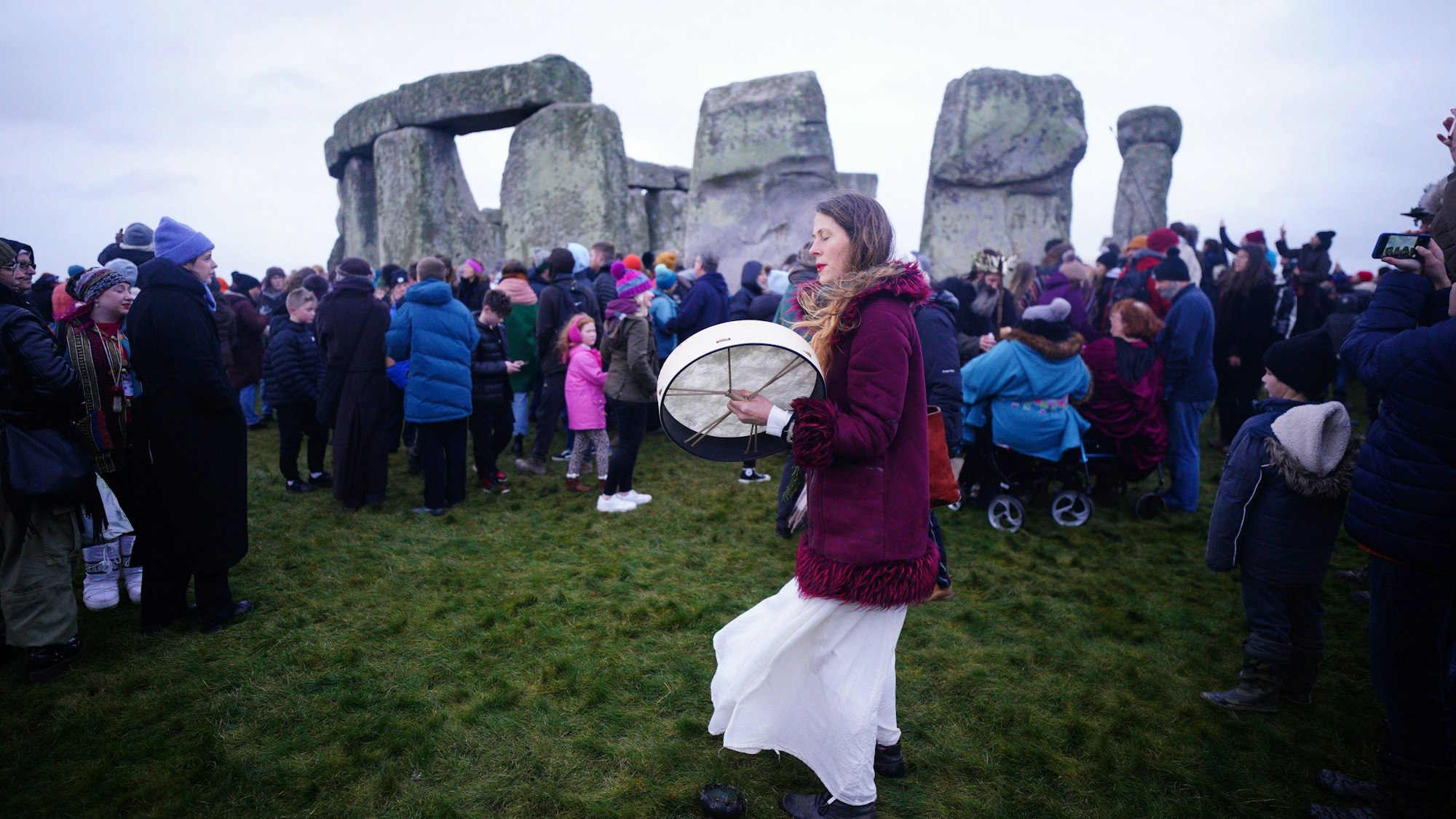 22.12.2023, Großbritannien, Amesbury: Menschen nehmen an den Feierlichkeiten zur Wintersonnenwende bei Sonnenaufgang am prähistorischen Monument Stonehenge auf der Salisbury Plain in Wiltshire teil. Foto: Ben Birchall/PA Wire/dpa +++ dpa-Bildfunk +++