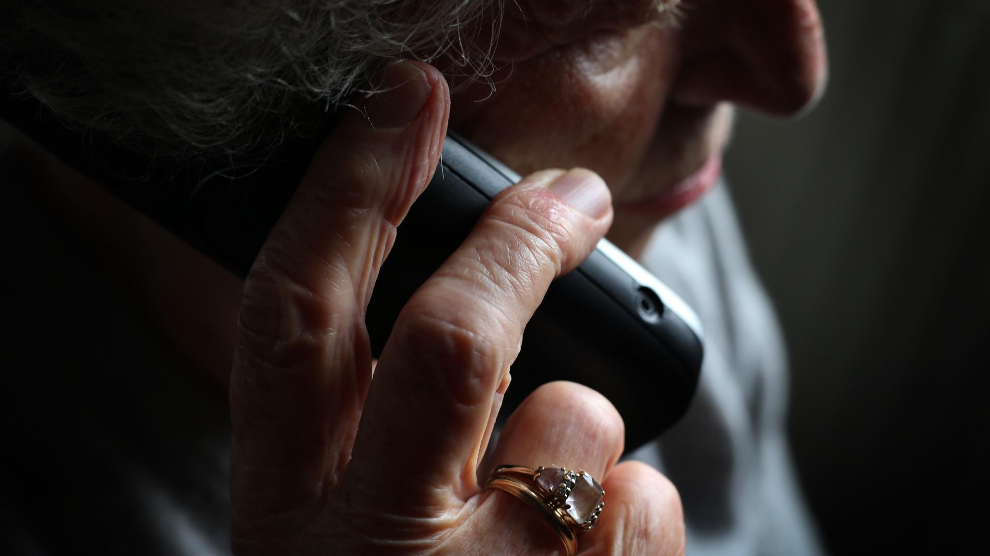 Eine ältere Frau telefoniert mit einem schnurlosen Festnetztelefon.